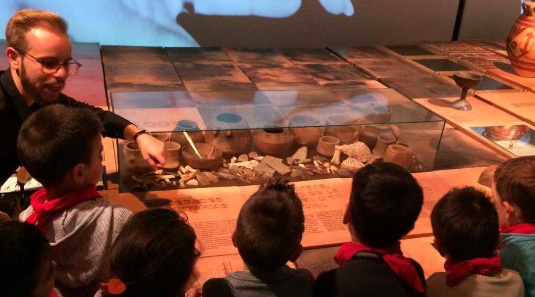 Varios niños atienden a una explicación sobre utensilios prehistóricos de un mediador cultural del Museo Memoria de Andalucía
