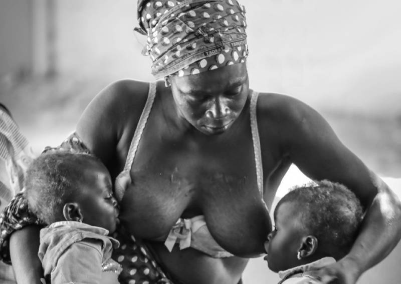 Fotografía de una mujer dando el pecho a dos niños