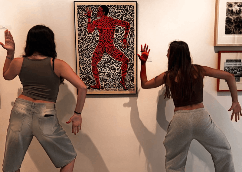 Dos personas interactuando con un cuadro.